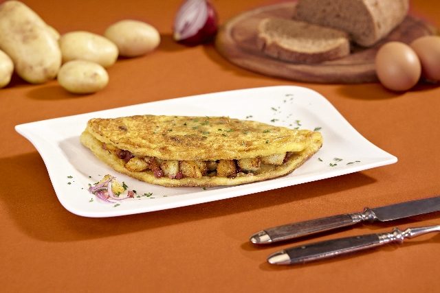 Bauernfrühstück mit Bratkartoffeln und Kasslerschulter im Omelett, auf einem weißen Teller